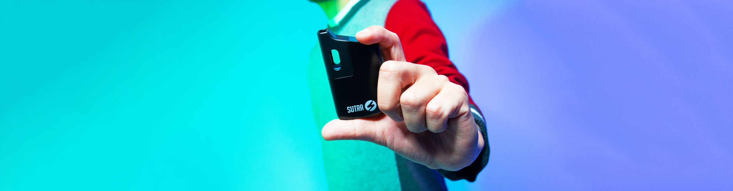 Man holding Sutra Mini in front of teal and purple studio background