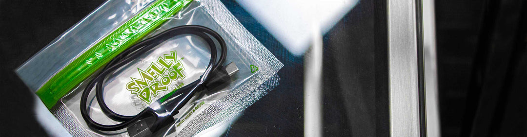 Small Sized Smelly Proof bag with USB Cable inside laying on glass table in normal lighting